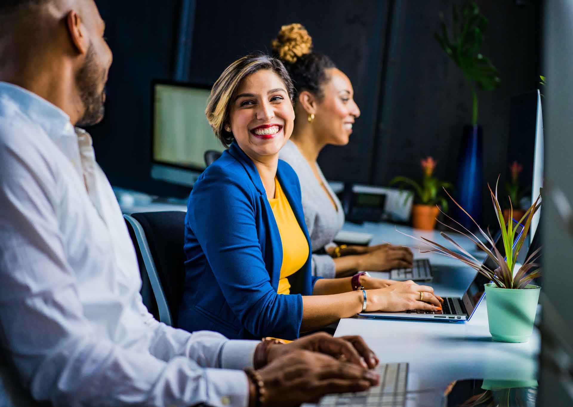 Two women and a man working at a desk